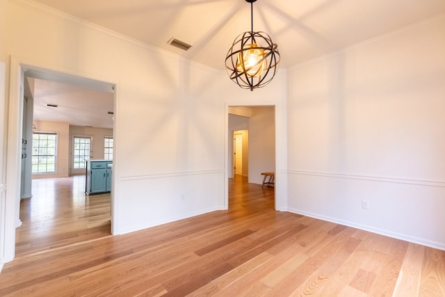 empty room featuring visible vents, baseboards, light wood-style flooring, ornamental molding, and a chandelier