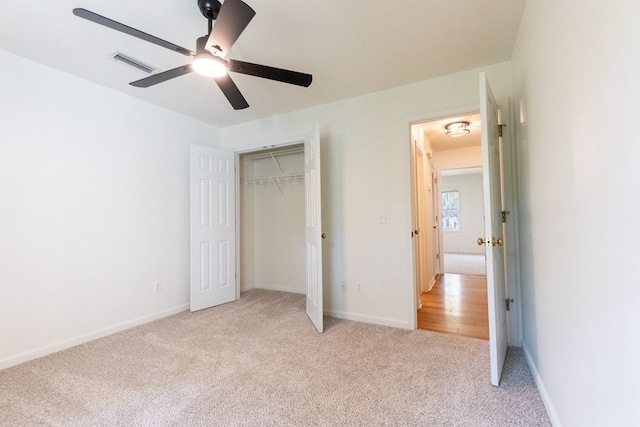 unfurnished bedroom featuring ceiling fan, light colored carpet, visible vents, baseboards, and a closet