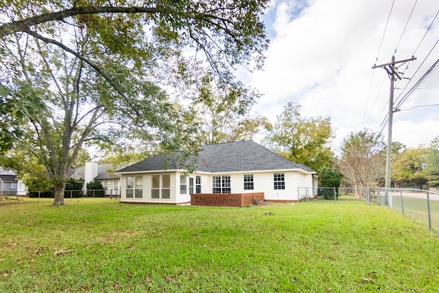 back of house featuring roof with shingles, a lawn, and a fenced backyard