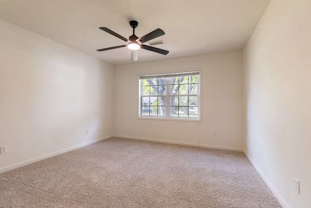 carpeted spare room with visible vents, a ceiling fan, and baseboards