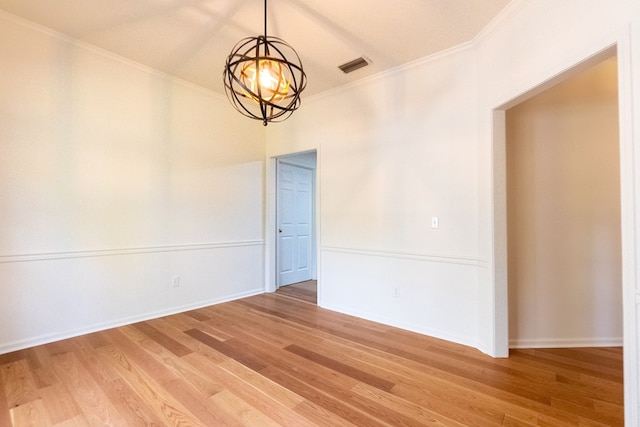 empty room with crown molding, visible vents, light wood-style flooring, an inviting chandelier, and baseboards