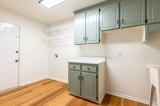 clothes washing area with washer hookup, light wood-type flooring, cabinet space, and baseboards