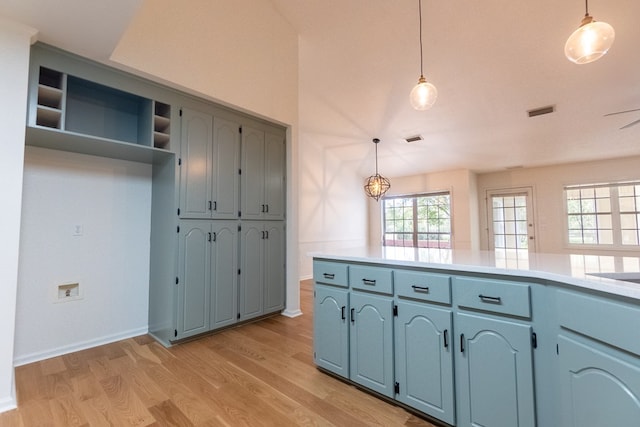 kitchen featuring visible vents, light countertops, decorative light fixtures, and light wood-style floors