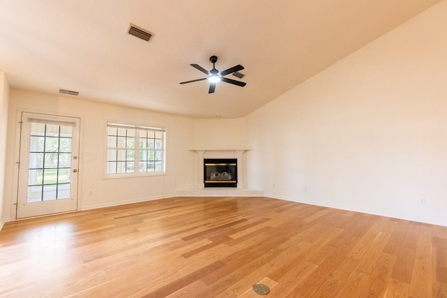 unfurnished living room with a glass covered fireplace, visible vents, ceiling fan, and light wood-style flooring