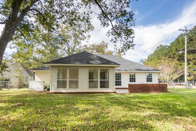 back of property featuring a yard, roof with shingles, fence, and a sunroom