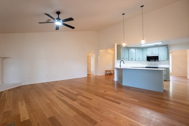 kitchen with open floor plan, light countertops, ceiling fan, and light wood finished floors