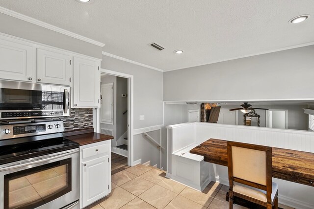 kitchen with light tile patterned floors, stainless steel appliances, backsplash, and white cabinetry