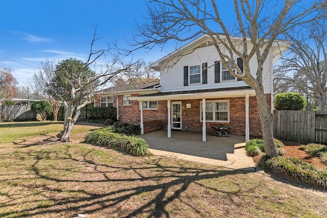 back of house with brick siding, a lawn, and fence