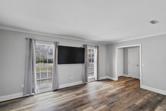 spare room with visible vents, ornamental molding, a textured ceiling, wood finished floors, and baseboards