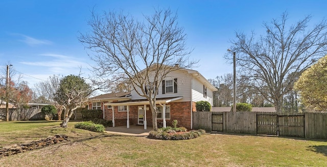 back of property featuring brick siding, a patio area, a yard, and fence