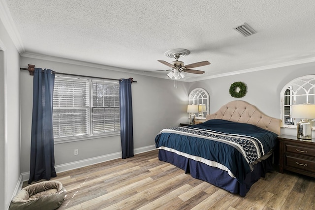 bedroom with wood finished floors, visible vents, baseboards, ornamental molding, and a textured ceiling