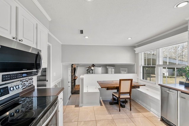 kitchen featuring crown molding, light tile patterned floors, visible vents, and stainless steel appliances