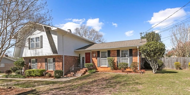 tri-level home featuring brick siding, a chimney, a front lawn, and fence