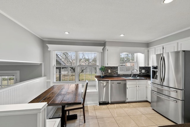 kitchen featuring backsplash, crown molding, appliances with stainless steel finishes, white cabinets, and a sink