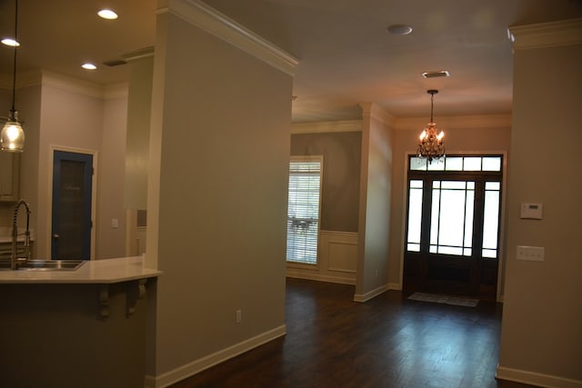 foyer featuring a wainscoted wall, dark wood finished floors, recessed lighting, a notable chandelier, and ornamental molding