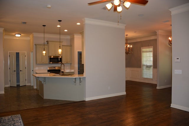 kitchen with stainless steel appliances, a kitchen breakfast bar, a sink, ceiling fan with notable chandelier, and light countertops