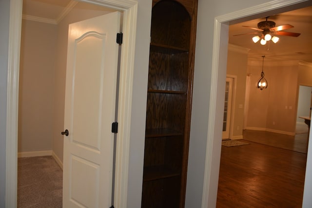 hallway featuring wood finished floors, baseboards, and ornamental molding