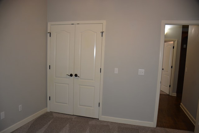 unfurnished bedroom featuring dark carpet, baseboards, and a closet