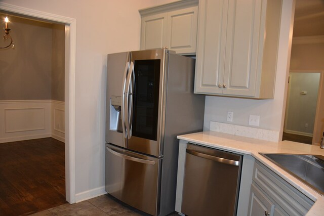 kitchen featuring light countertops, a sink, stainless steel appliances, and wainscoting