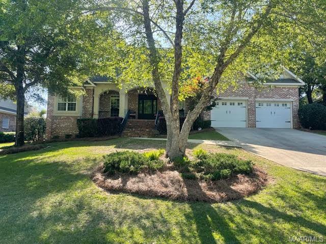 obstructed view of property with brick siding, driveway, and a front yard