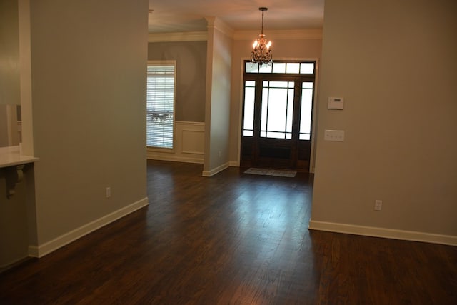 foyer with an inviting chandelier, dark wood-style flooring, crown molding, and plenty of natural light