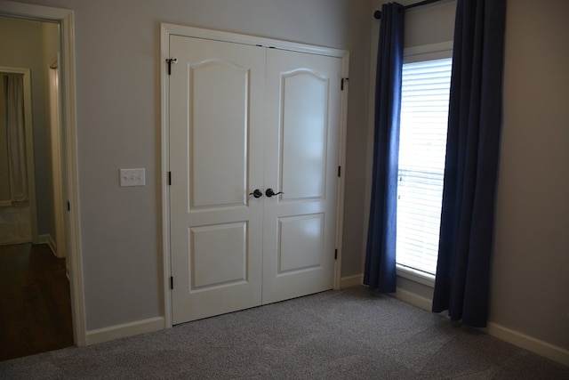 unfurnished bedroom with baseboards, multiple windows, and a closet