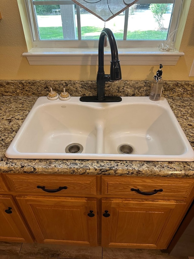 interior details featuring stone countertops, a sink, and brown cabinets