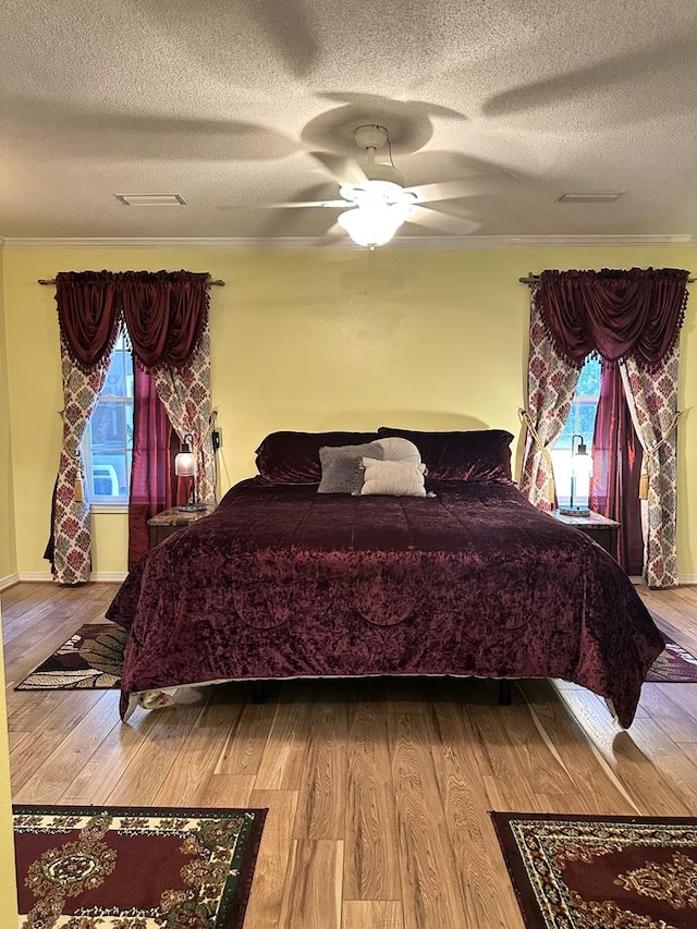 bedroom featuring a textured ceiling, multiple windows, and wood finished floors