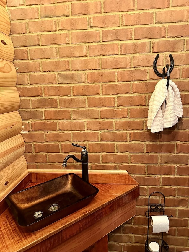 bathroom with a sink and brick wall