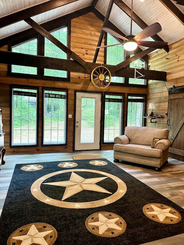 living area with a wealth of natural light, wood finished floors, wooden walls, and high vaulted ceiling