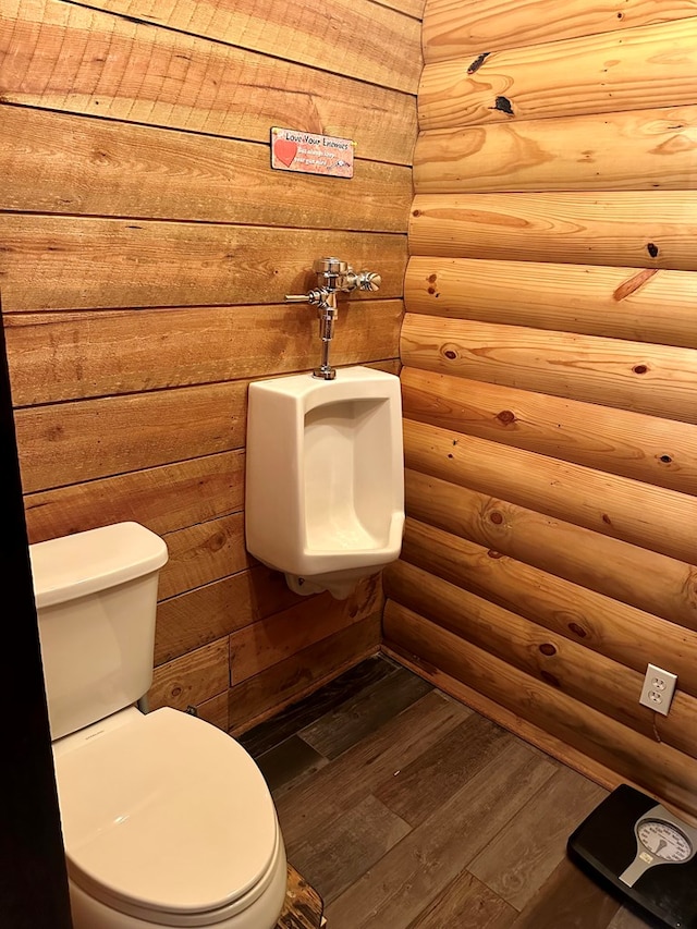 bathroom with rustic walls, wood finished floors, and toilet