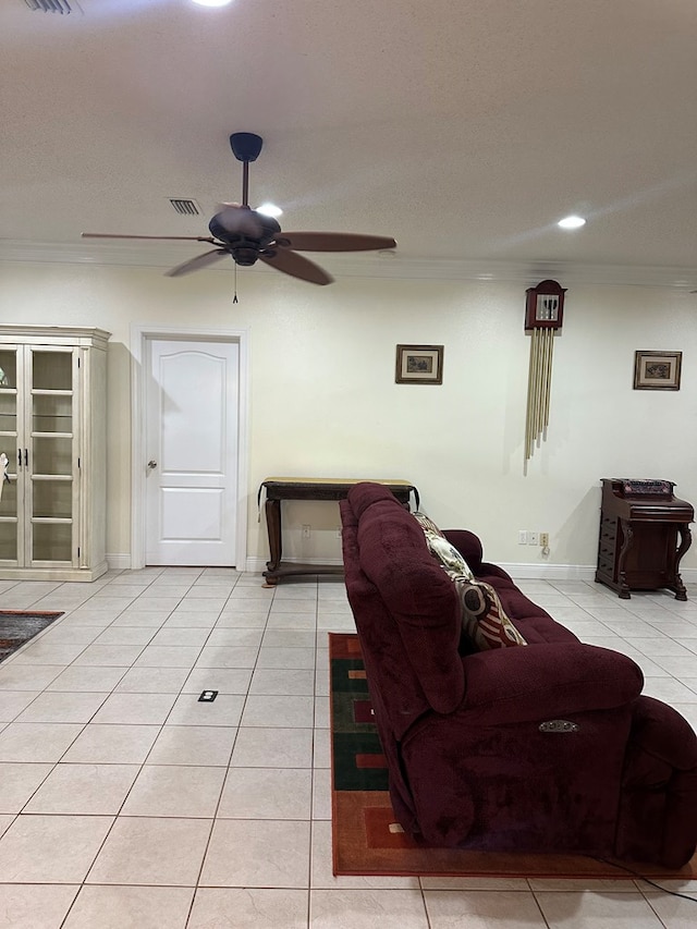 living room with crown molding, light tile patterned flooring, a ceiling fan, baseboards, and visible vents