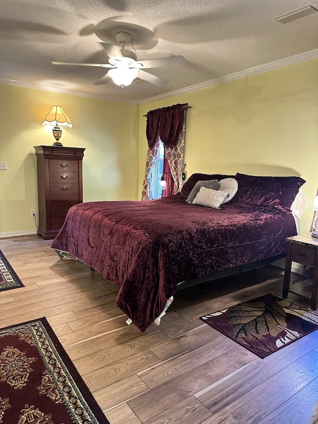 bedroom featuring visible vents, ornamental molding, a textured ceiling, and hardwood / wood-style floors