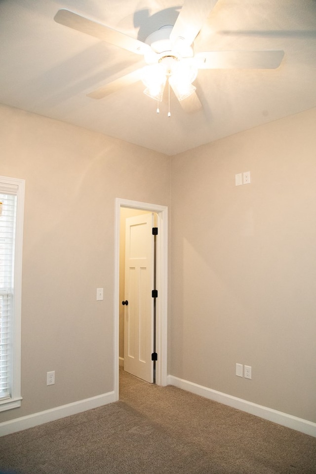 carpeted spare room with ceiling fan