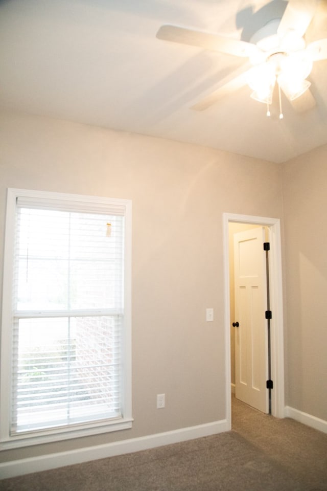 carpeted spare room featuring ceiling fan