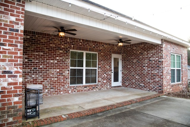 view of exterior entry with ceiling fan and a patio