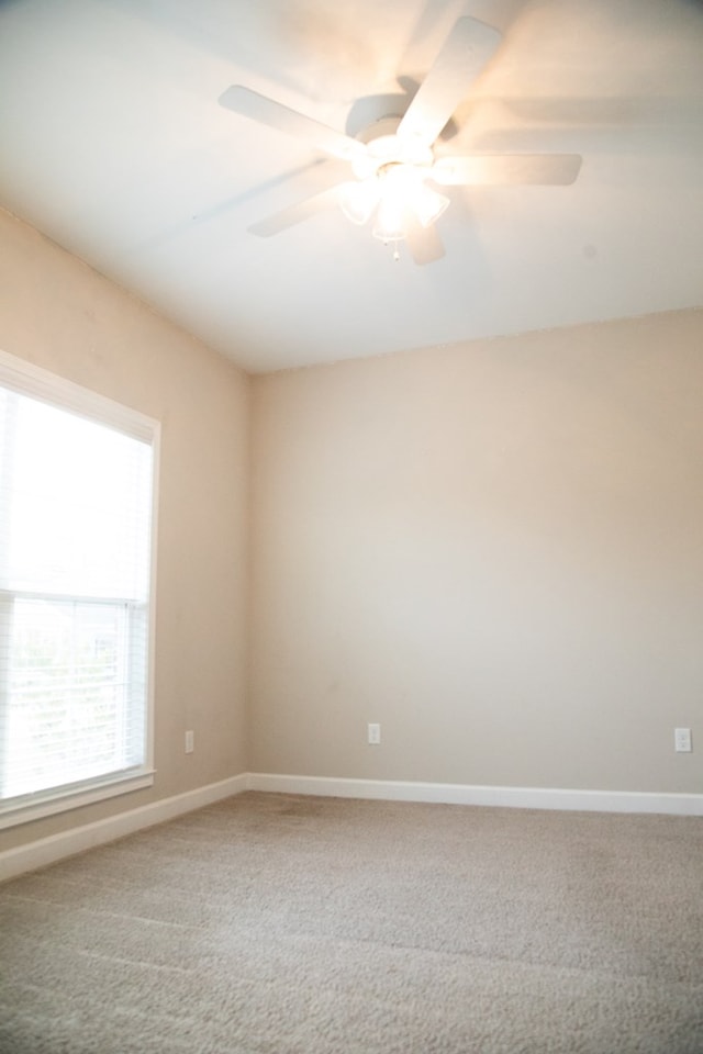 carpeted spare room featuring ceiling fan