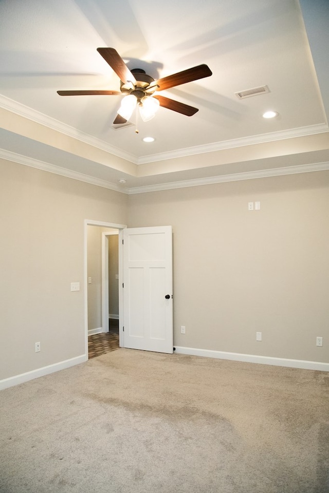 carpeted spare room with a tray ceiling, ornamental molding, and ceiling fan