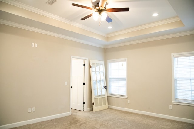 carpeted empty room featuring ceiling fan, ornamental molding, and a tray ceiling