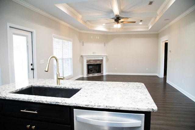 kitchen with a fireplace, dishwasher, sink, light stone counters, and crown molding