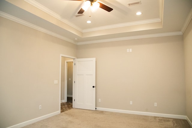 spare room with a raised ceiling, ornamental molding, light carpet, and ceiling fan