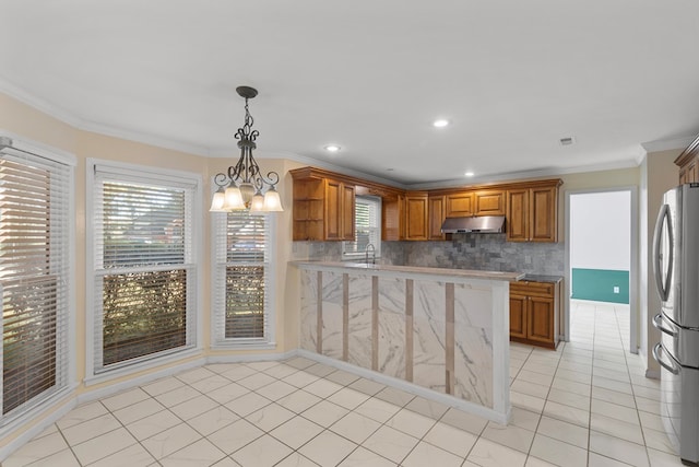 kitchen featuring backsplash, stainless steel refrigerator, crown molding, and pendant lighting