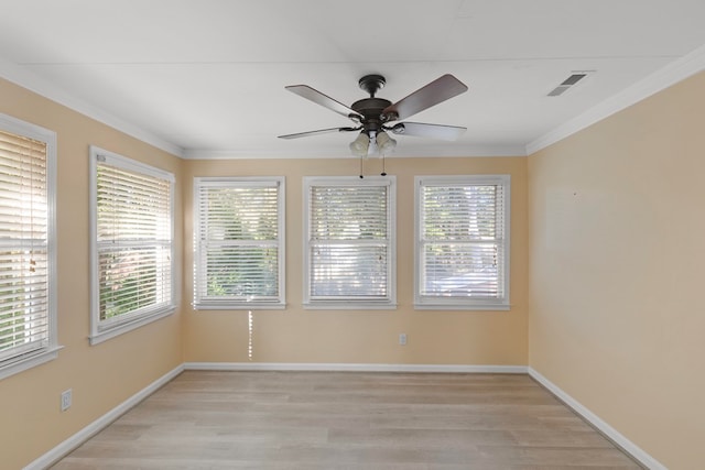 empty room featuring a wealth of natural light, light hardwood / wood-style flooring, ceiling fan, and ornamental molding