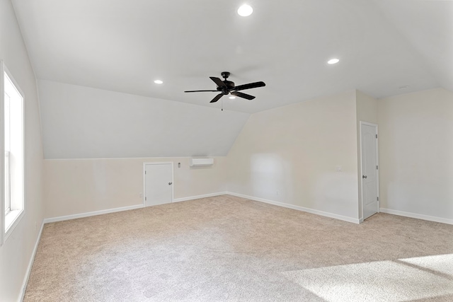 additional living space featuring a wall unit AC, ceiling fan, light colored carpet, and vaulted ceiling