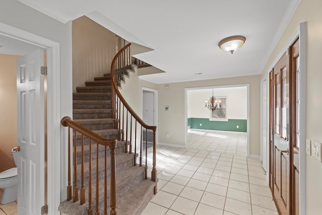 tiled entryway featuring an inviting chandelier and crown molding