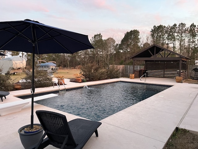 pool at dusk with a gazebo, a diving board, and a patio