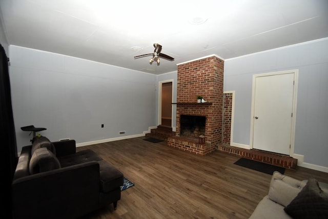 living room featuring a ceiling fan, wood finished floors, a brick fireplace, baseboards, and visible vents