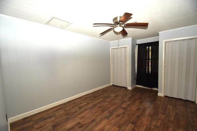 unfurnished room with crown molding, attic access, dark wood-style flooring, baseboards, and ceiling fan