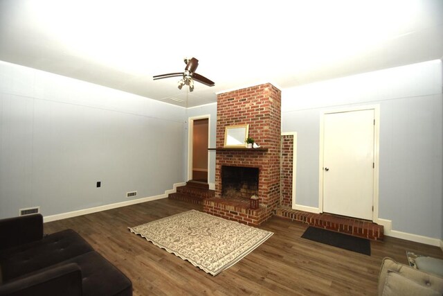living room with visible vents, a fireplace, wood finished floors, and a ceiling fan