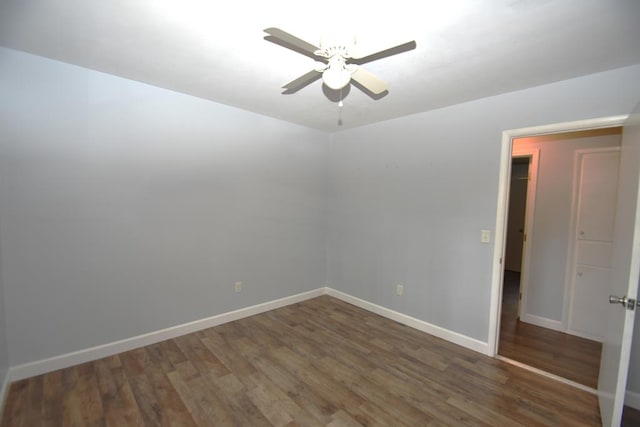 empty room featuring baseboards, wood finished floors, and a ceiling fan